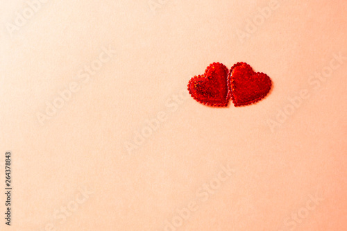 Two sparkling hearts together on coral background