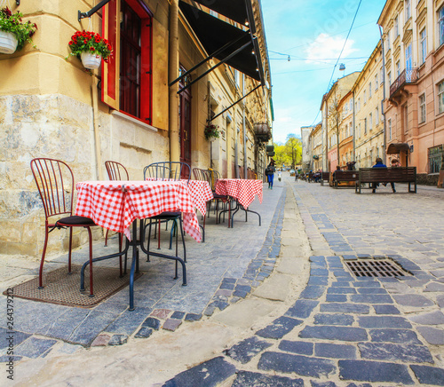 Outdoor cafe in the old town. Summer cafe in the narrow old street.  Vintage tables on narrow paved  street among houses and between walls in Lviv, Ukraine. Concept  - travel, landmarks