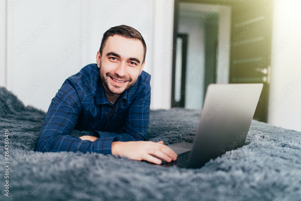 Male freelancer working with laptop in bed at home Male freelancer working with laptop in bed at home