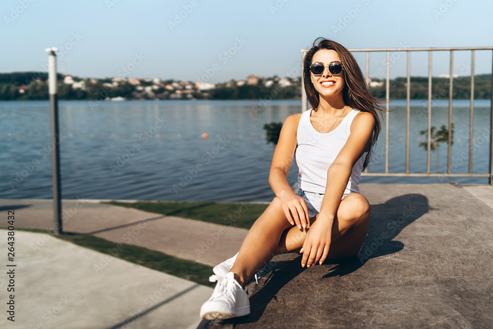 Pretty young brunette girl with long hair relaxing outdoor in the park near lake. Pretty young brunette girl with long hair relaxing outdoor in the park near lake.