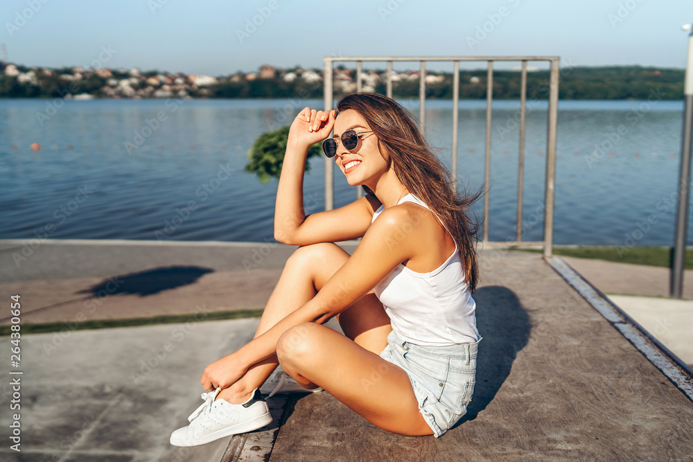 Pretty young brunette girl with long hair relaxing outdoor in the park near lake. Pretty young brunette girl with long hair relaxing outdoor in the park near lake.