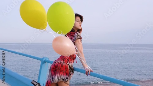 La felicità di una ragazza che corre su un ponte sul mare con palloncini colorati di elio. photo