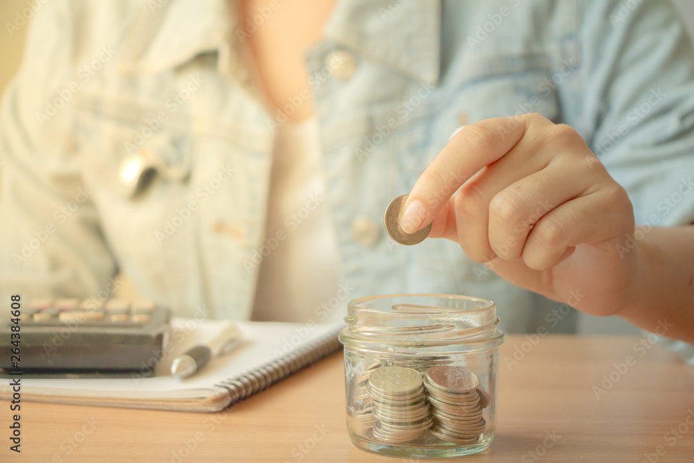 Business woman hand putting coin into glass jar.saving money and financial concept. Financial planning for the future.