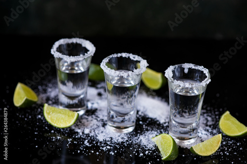 Tequila shot with lime and salt on black background
