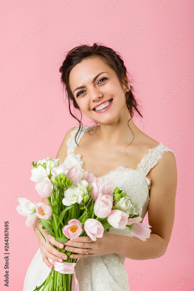 beautiful bride with wedding bouquet of pink tulips on pink background
