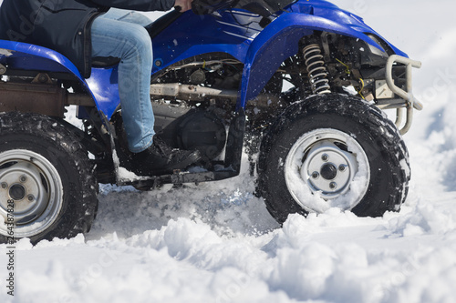 A person riding a bright blue snowmobile in the forest