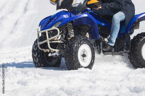 A winter forest. A young woman riding a blue snowmobile