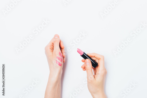 Woman's hands apply test sample of pink lipstick