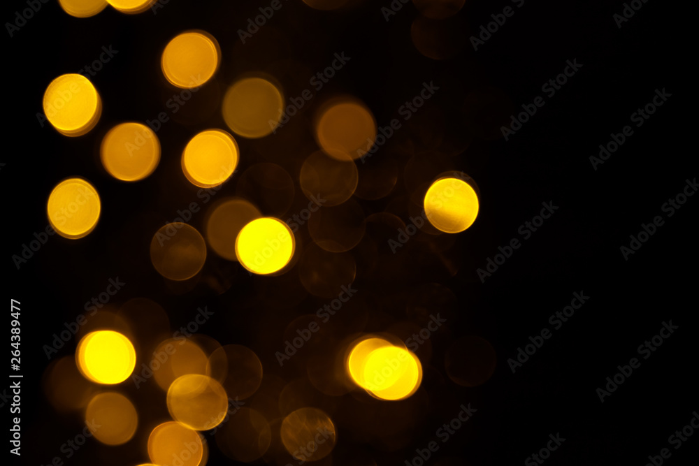 Obraz premium Abstract gold bokeh on black background. Defocused yellow lights, abstract texture