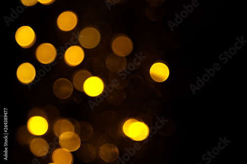 Abstract gold bokeh on black background. Defocused yellow lights, abstract texture