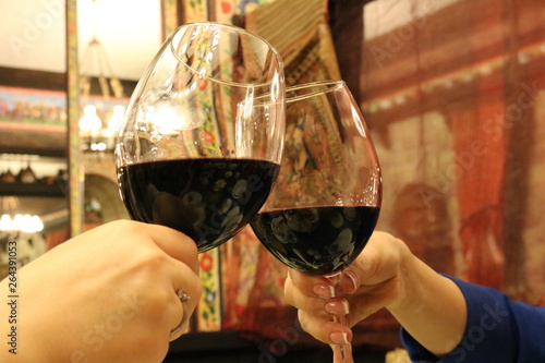 A glass of red wine.Toasting with wine glasses. Two wine glasses clink at the party, close-up view of friends clinking glasses of red wine