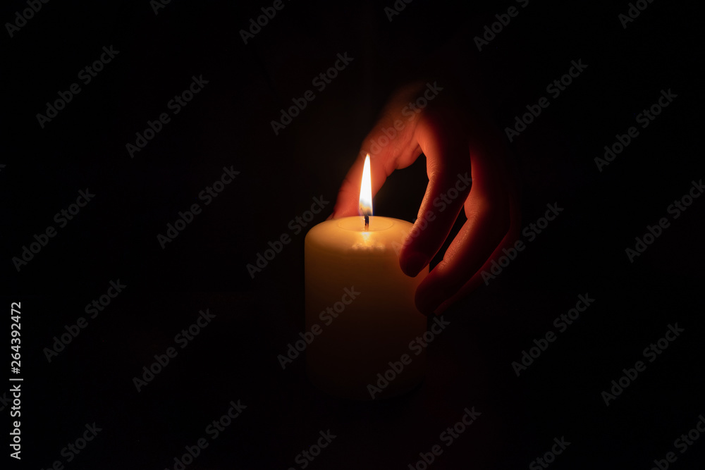 Female hand holding a burning candle in the dark Female hand holding a burning candle in the dark