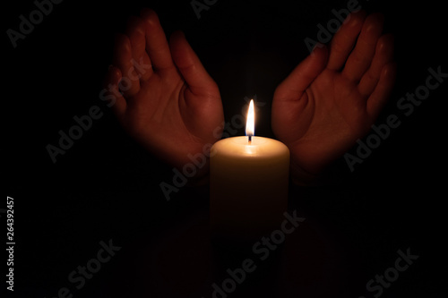 Hands in the dark over burning candles