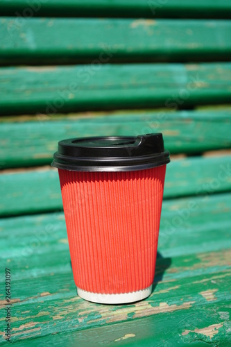 red coffee cup on the bench in garden 