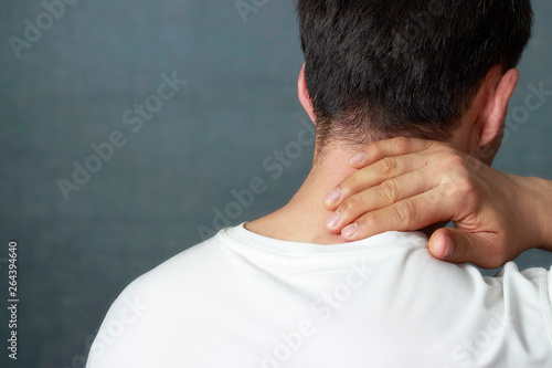 Photography A man is massaging a sore neck, close-up, rear view.