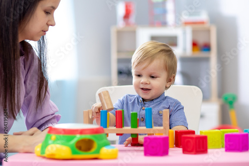 Nursery baby and caregiver play at table in daycare centre