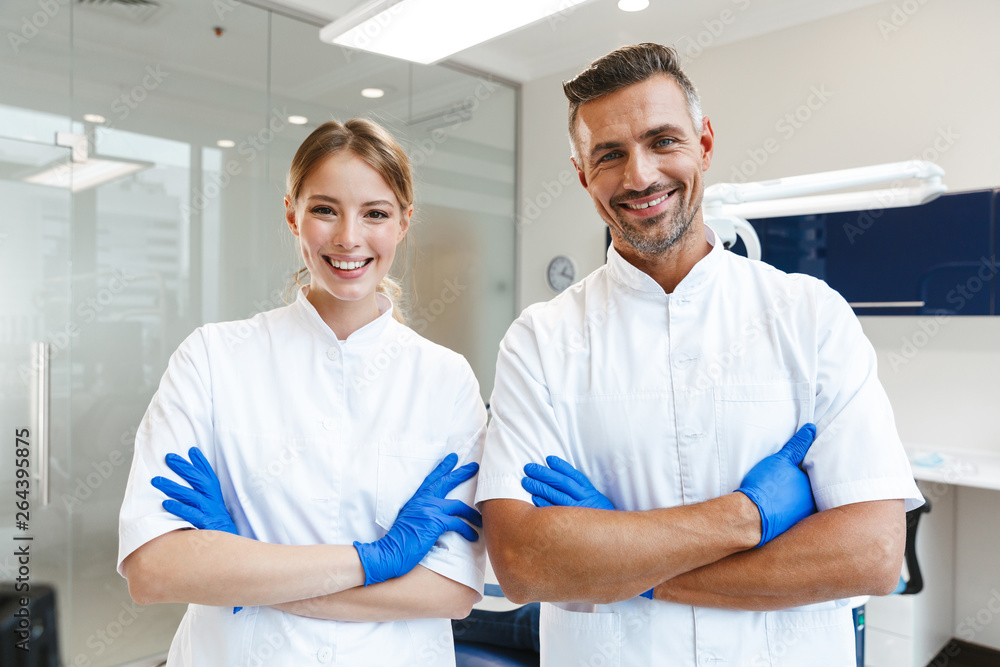 Obraz premium Image of handsome happy man doctor and young woman assistant working in medical dentist center