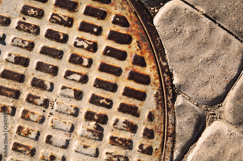Abstract background of rusty manhole cover and paving tiles.