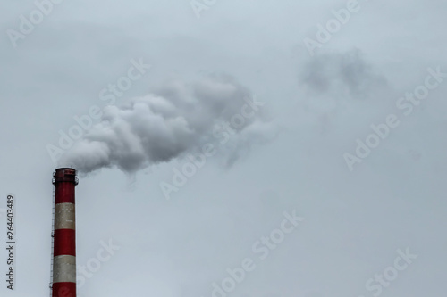 The pipe from which the smoke goes against the gray sky. The concept of air pollution, CO2, carbon dioxide gas, exhaust gases.