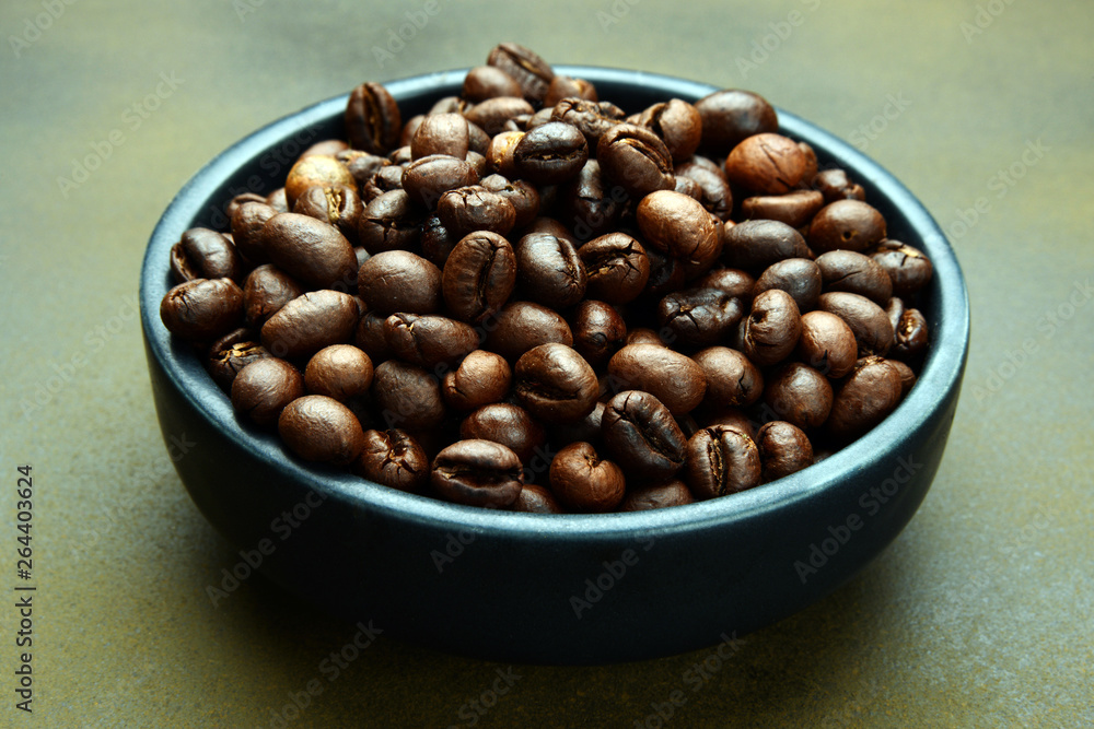 Roasted Coffee beans in a bowl on rusty background Roasted Coffee beans in a bowl on rusty background