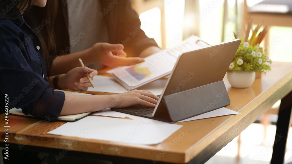 Businesspeople using digital tablet and paper work in office together