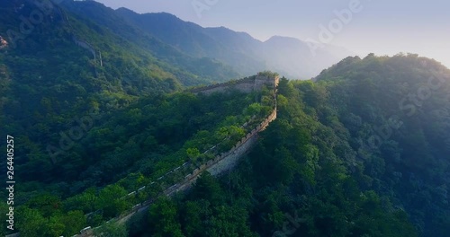 Drone shot of Great Wall of China in Mutianyu (China) at sundown in autumn flying forward over inaccessible parts of the Wall photo