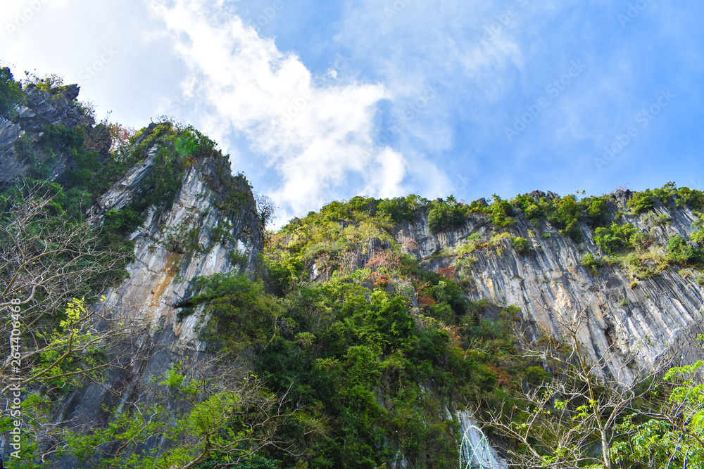 A rock formation's cliff with the blue sky above it as viewed from the ground. In El Nido, Palawan, Philippines.