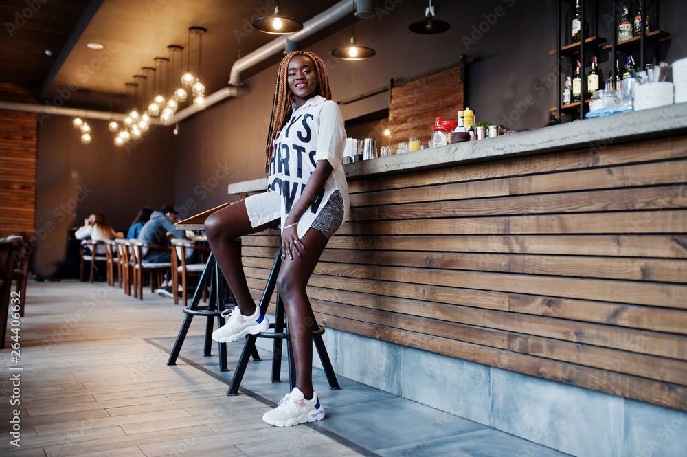 Fototapeta premium Beautiful african woman in stylish casual clothes sitting near bar counter.