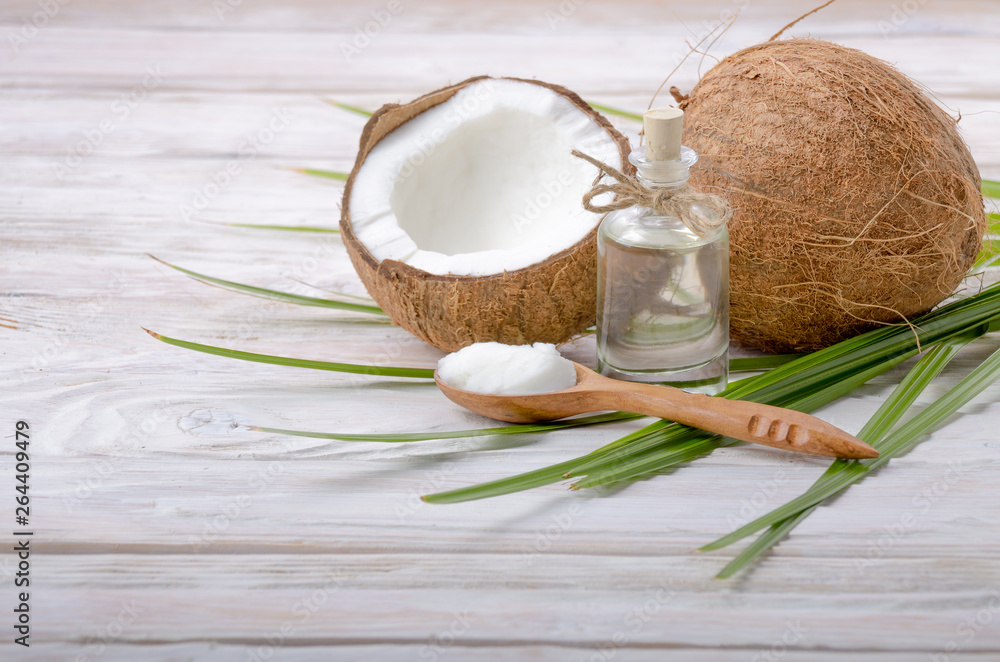 Coconut shell pieces and palm leaves on white wooden table Coconut shell pieces and palm leaves on white wooden table