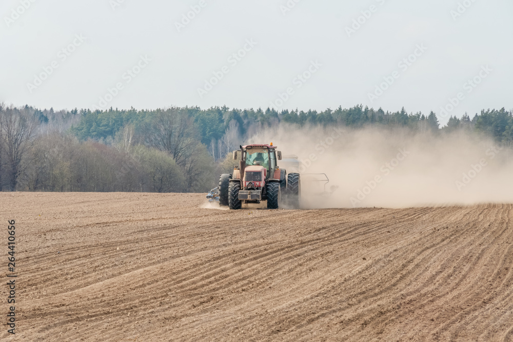 Obraz premium Farmer in tractor preparing land with seedbed cultivator as part of pre seeding activities in early spring season of agricultural works at farmlands.