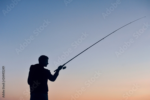 Silhouette of a fisherman at sunset against the sky