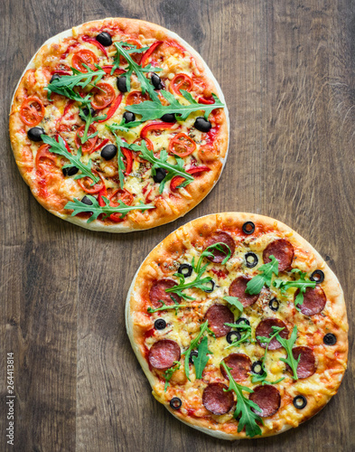 Pepperoni Pizza and Pizza with Mozzarella cheese, Tomatoes, pepper, olive, Spices and Fresh arugula. Pizza Margherita or Margarita on wooden table background