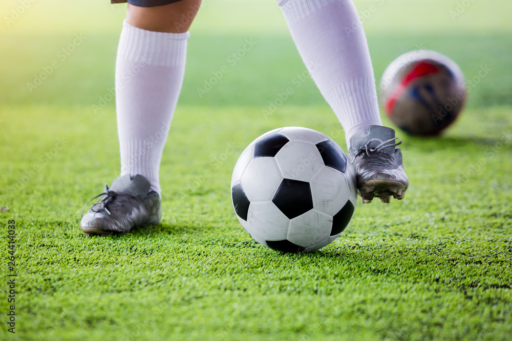 kid soccer player jogging with control ball to shoot to goal on artificial turf.