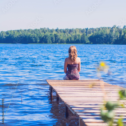 Anonymous woman sitting in the sun on a pier by the lake in the woods. Toned. © Ольга Ким