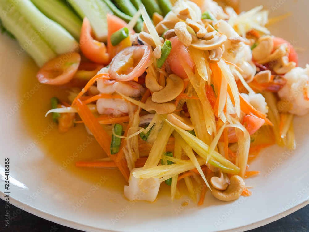Authentic traditional salad with green papaya, fresh vegetables and herbs, seafood on plate in Thai restaurant Authentic traditional salad with green papaya, fresh vegetables and herbs, seafood on plate in Thai restaurant