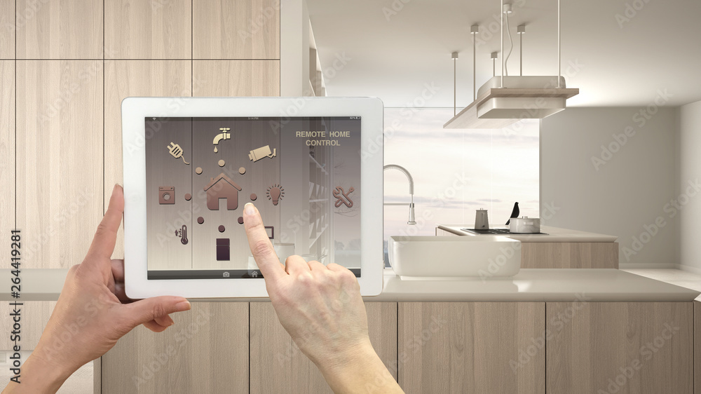 Smart remote home control system on a digital tablet. Device with app icons. Modern kitchen with wooden details in contemporary apartment background, architecture interior design Smart remote home control system on a digital tablet. Device with app icons. Modern kitchen with wooden details in contemporary apartment background, architecture interior design