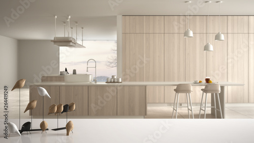 White table top or shelf with minimalistic bird ornament, birdie knick - knack over blurred contemporary white and wooden kitchen with island and stools, modern interior design photo