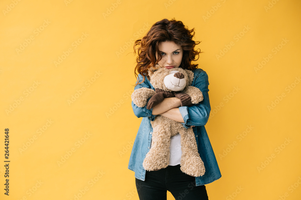 upset curly redhead young woman holding teddy bear on orange upset curly redhead young woman holding teddy bear on orange