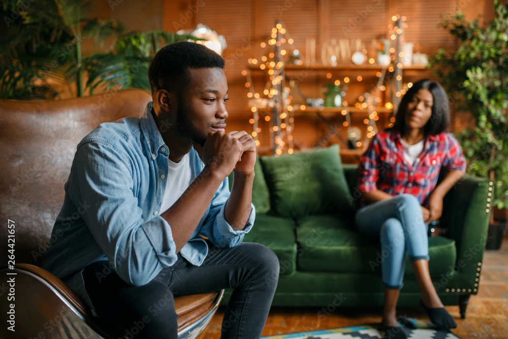 Black man sitting in a chair against his woman Black man sitting in a chair against his woman