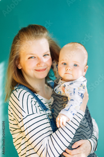 Family photo shoot in the spring summer theme. Young mother and son in a photo Studio on a green background.