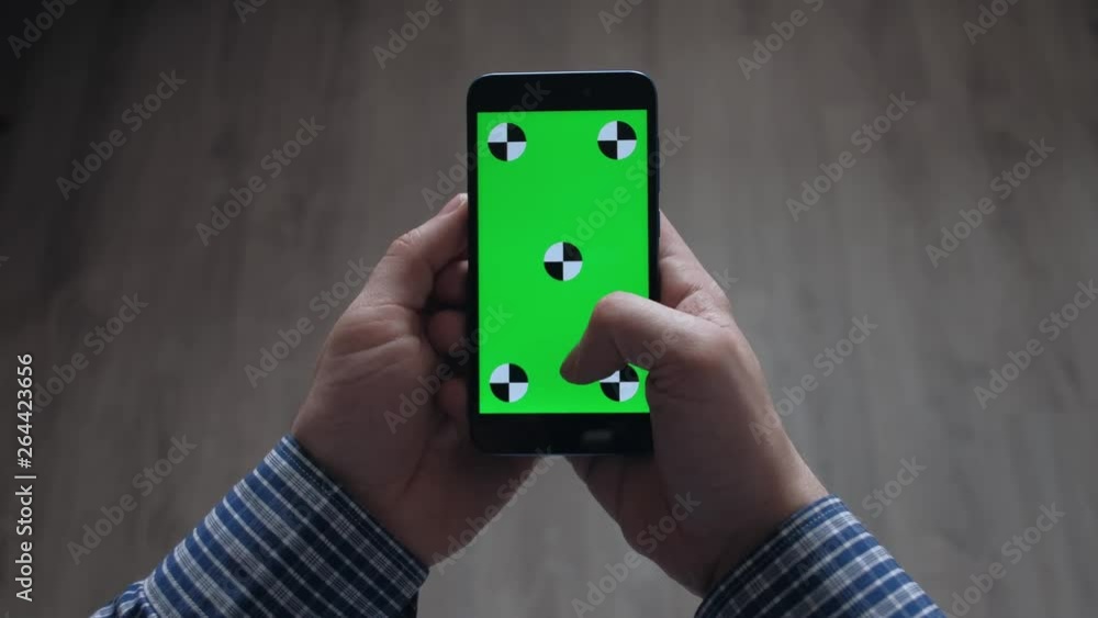 close up - Hands of man using smartphone with green screen ion gray background. Scroll up with your finger. close up - Hands of man using smartphone with green screen ion gray background. Scroll up with your finger.