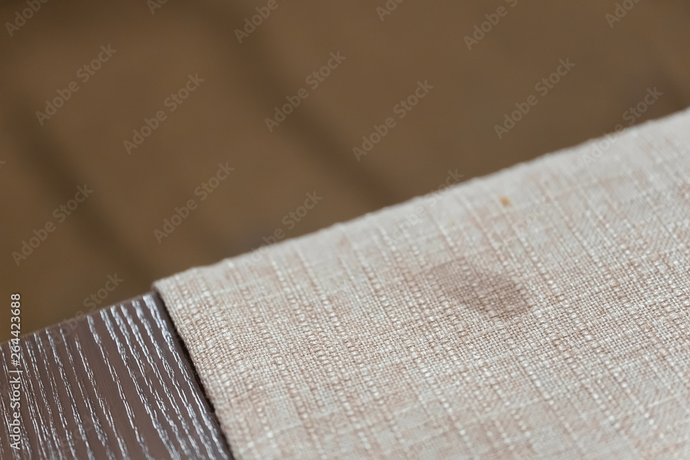 Decorative beige cloth for the table. A drop of milk on a napkin. Soiled material. The texture of the fabric. - obrazy, fototapety, plakaty 
