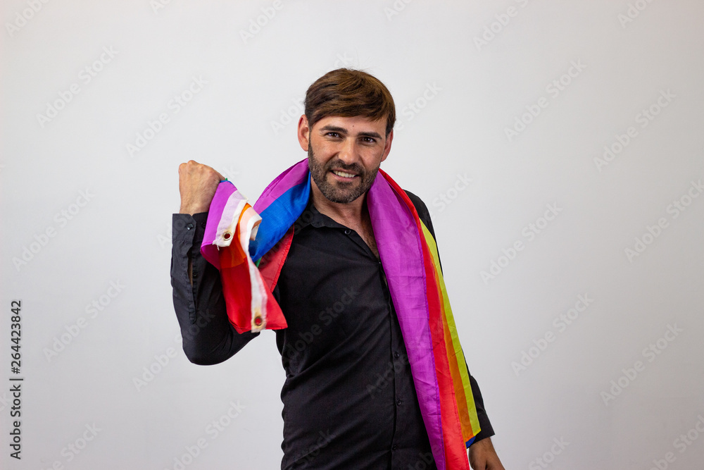 Portrait of handsome young man with gay pride movement LGBT Rainbow flag and brown hair looking euphoric, looking at the camera. Isolated on white background. Portrait of handsome young man with gay pride movement LGBT Rainbow flag and brown hair looking euphoric, looking at the camera. Isolated on white background.