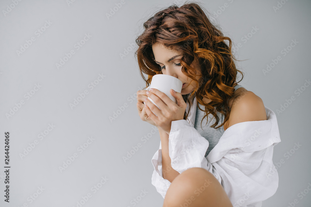 pretty girl with curly red hair drinking coffee on grey pretty girl with curly red hair drinking coffee on grey