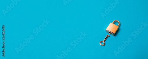 Flat lay protection concept. Locked padlock and key on the blue background. photo