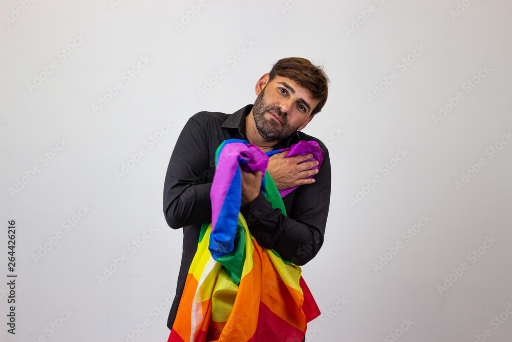 Portrait of handsome young man with gay pride movement LGBT Rainbow flag and brown hair looking impatient, looking at the camera. Isolated on white background. Portrait of handsome young man with gay pride movement LGBT Rainbow flag and brown hair looking impatient, looking at the camera. Isolated on white background.