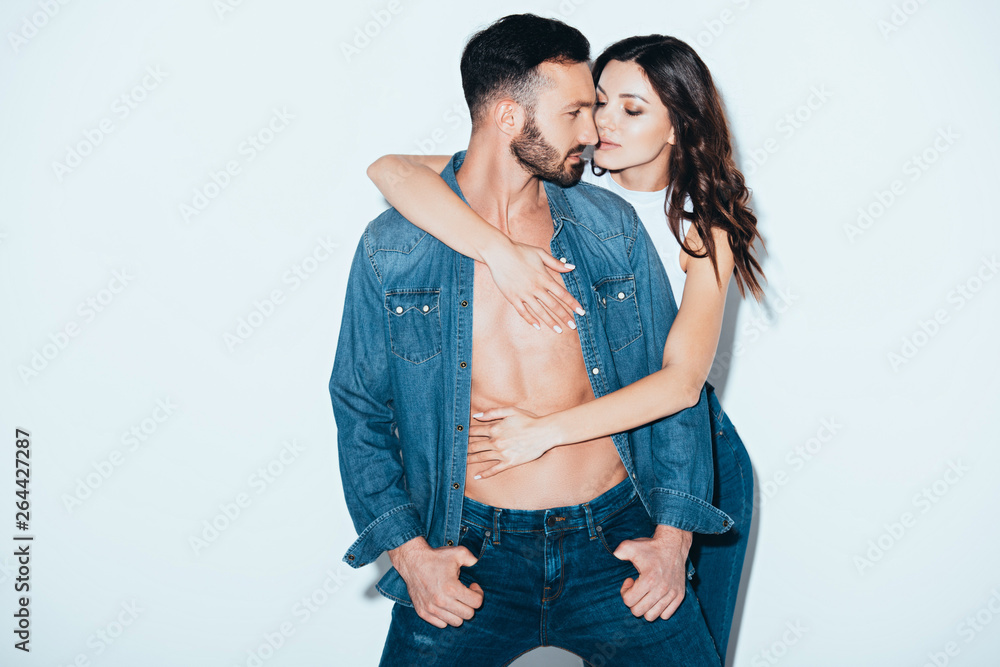 Naklejka premium pretty young woman embracing bearded boyfriend on grey