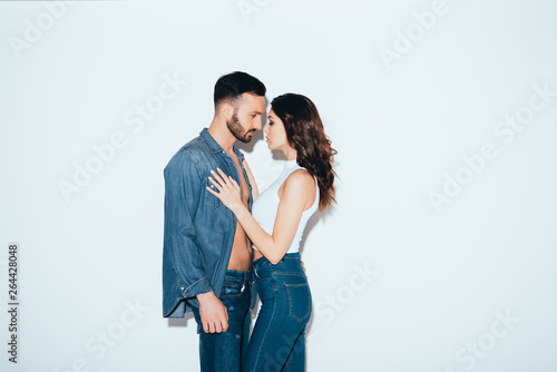 stylish couple in jeans standing together on grey