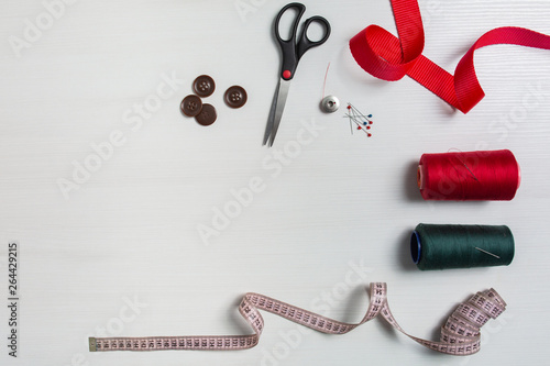 Sewing accessories on a white background, sewing threads and needles, scissors buttons and sewing centimeter.