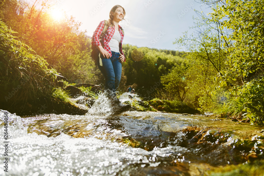 Woman crossing the river in the wild valley Woman crossing the river in the wild valley